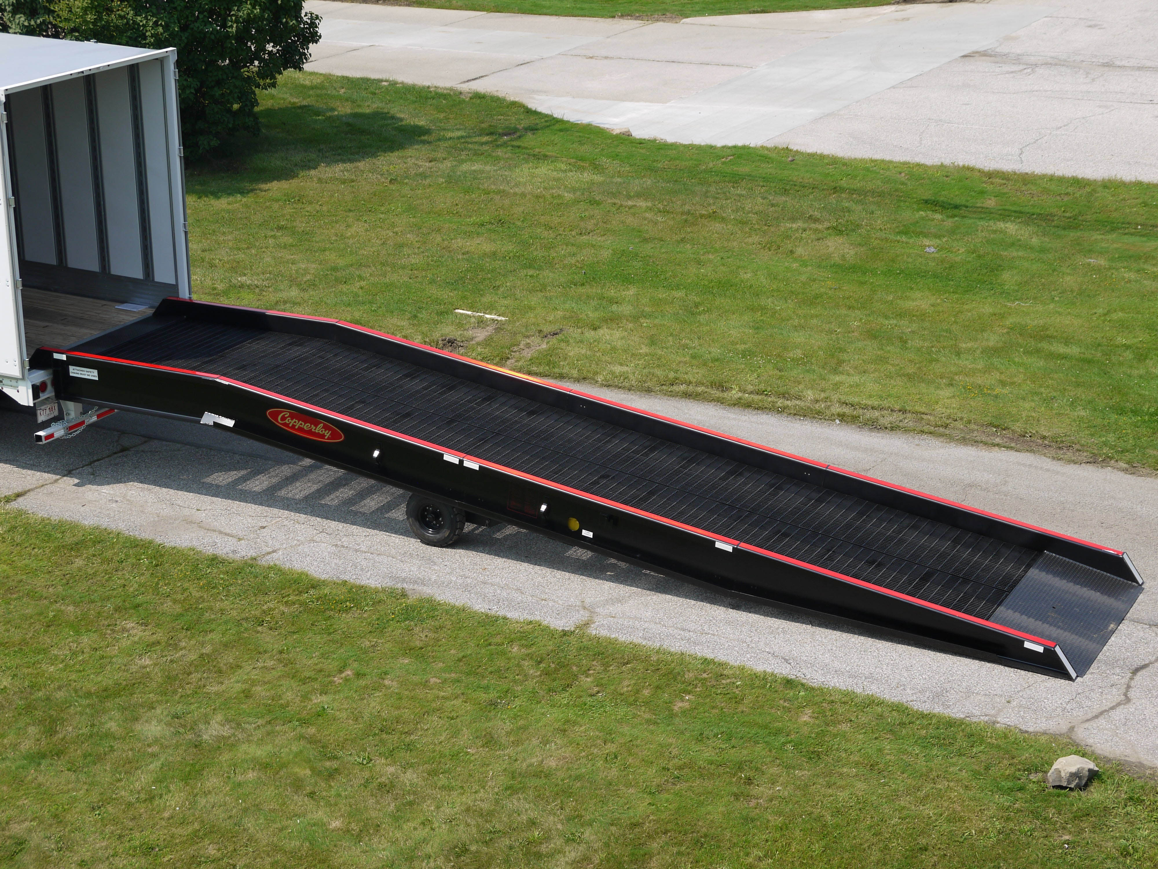 A Copperloy portable yard ramp connected to the back of a truck.